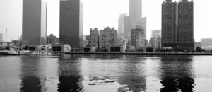 Black and white cityscape of Kaohsiung skyline with reflections on the water.